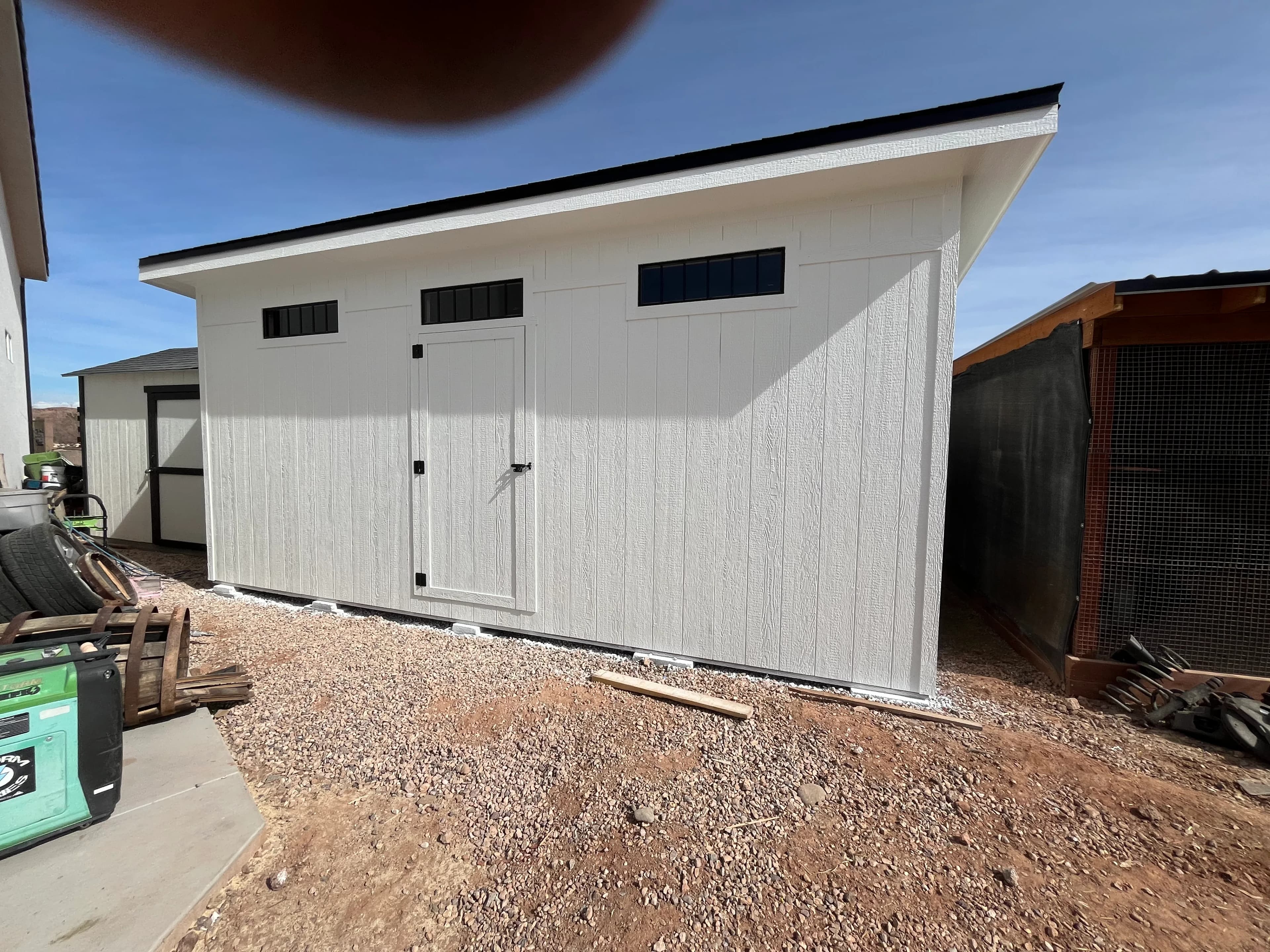 Modern white lean-to shed with double doors and transom windows built by Quality Creations in Southern Utah