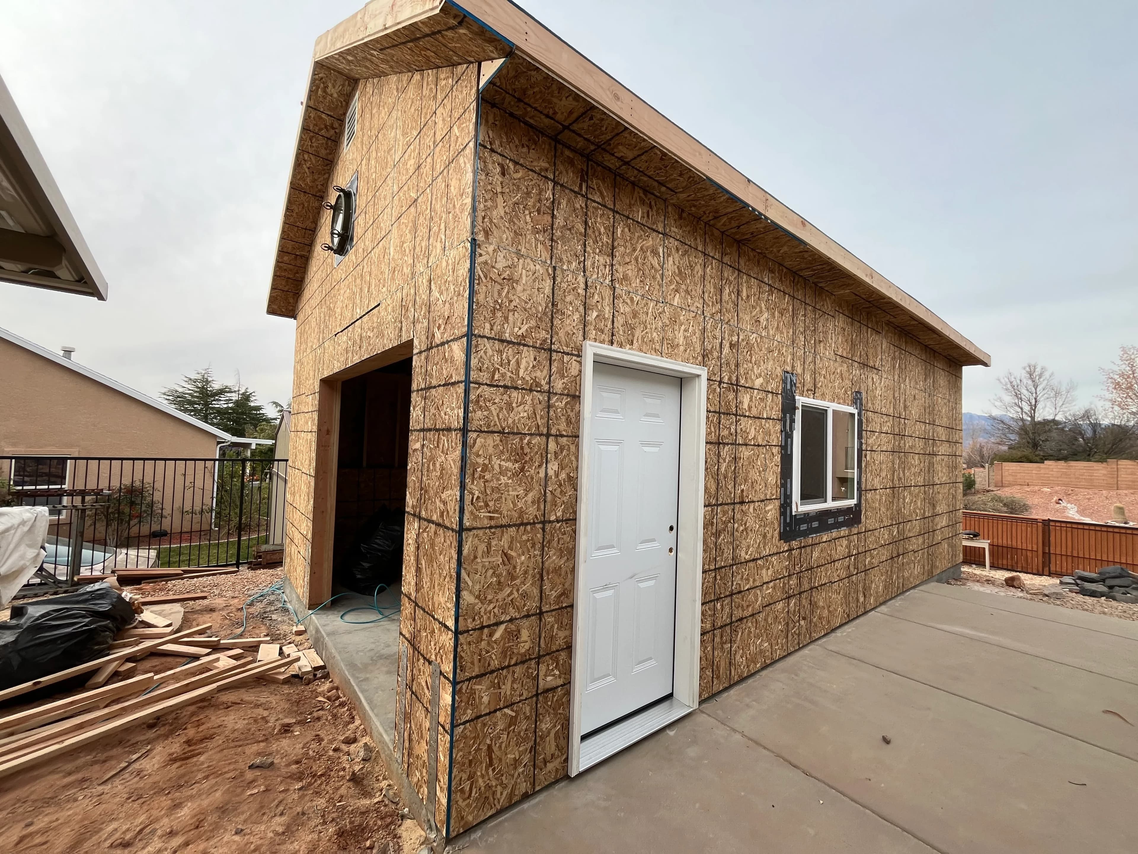 Side view of a Quality Creations custom garage showing white entry door, window, and gable roofline