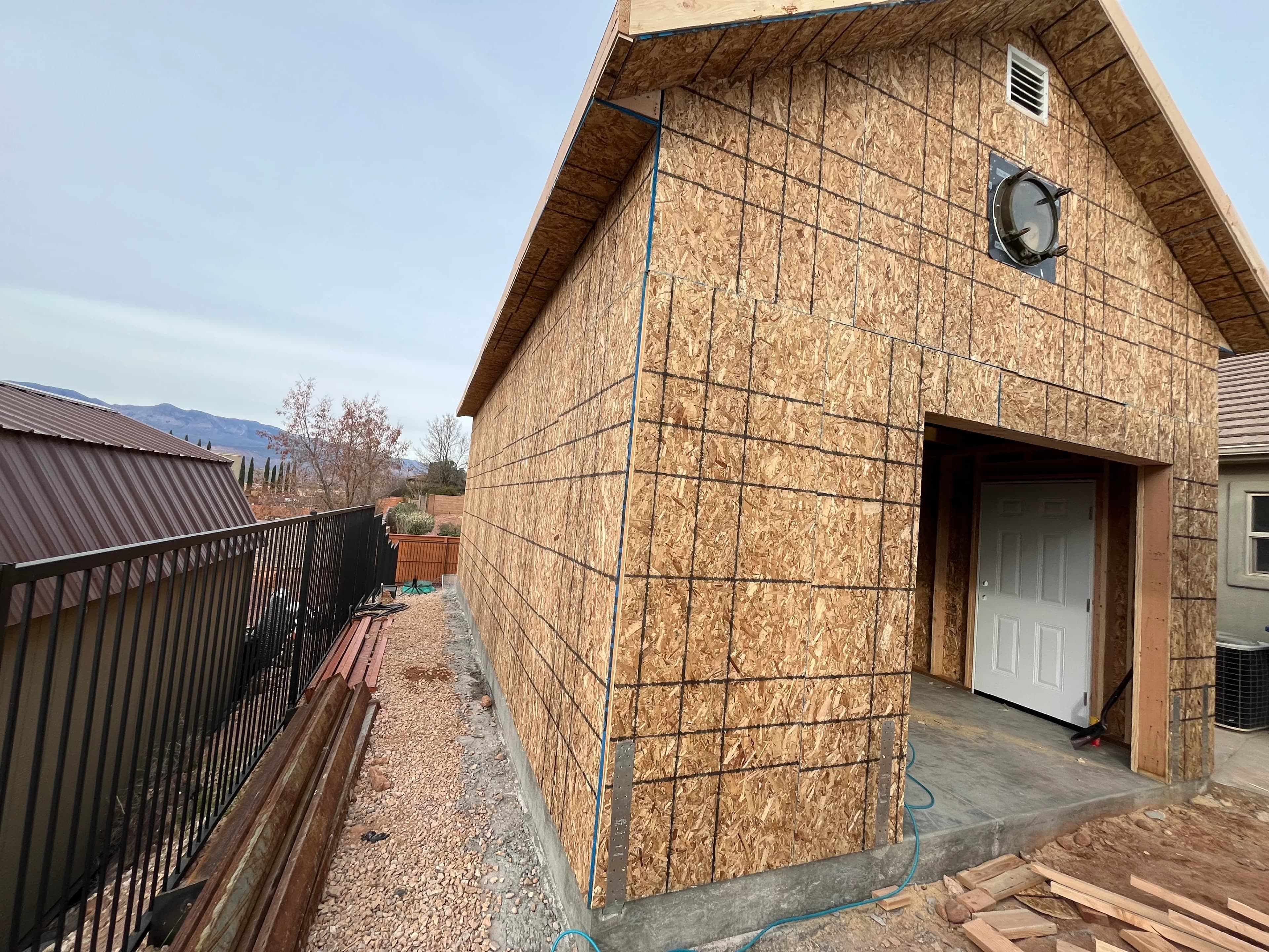 Rear angle of a detached garage build in Southern Utah showing gambrel-style roofline and OSB sheathing