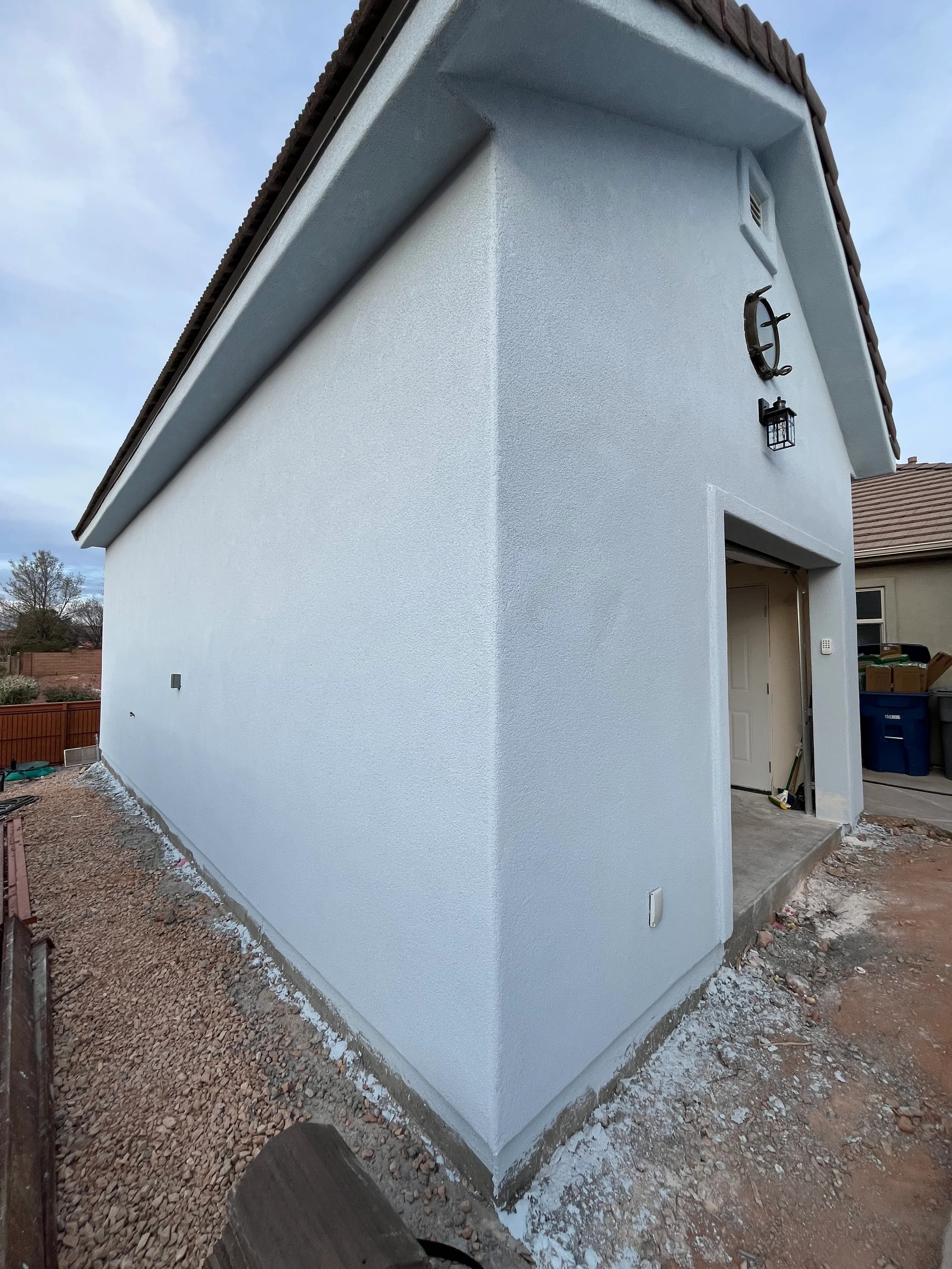 White stucco detached garage with gable roof, decorative lantern, and side entry door in Southern Utah